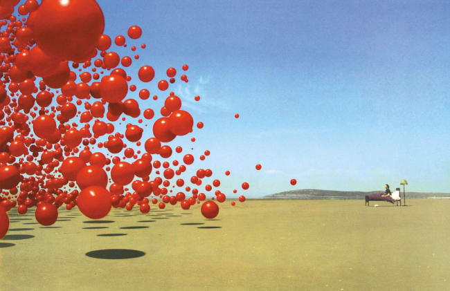 A shot of balloons flying away with someone in a bed in the middle of a desert