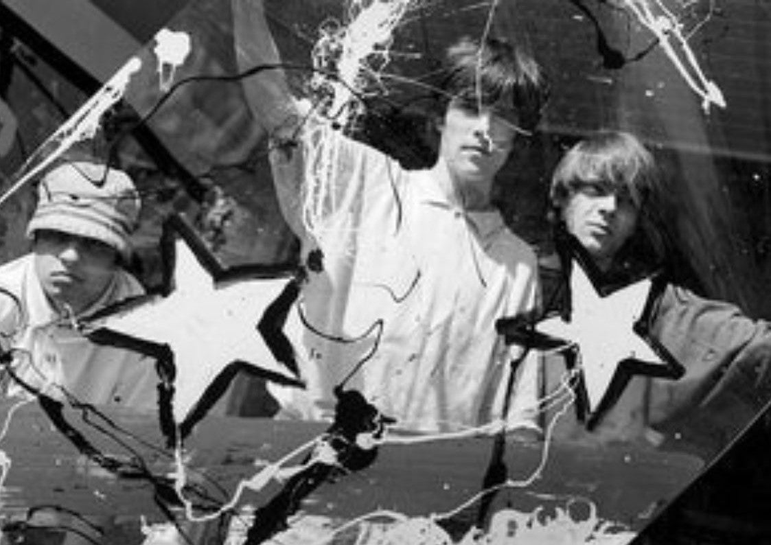A black and white Kevin Cummins shot of the members of The Stone Roses (Left to right: Paul Slattery, Kevin Cummins & Ian Tilton) decorated with paint splatters and stars
