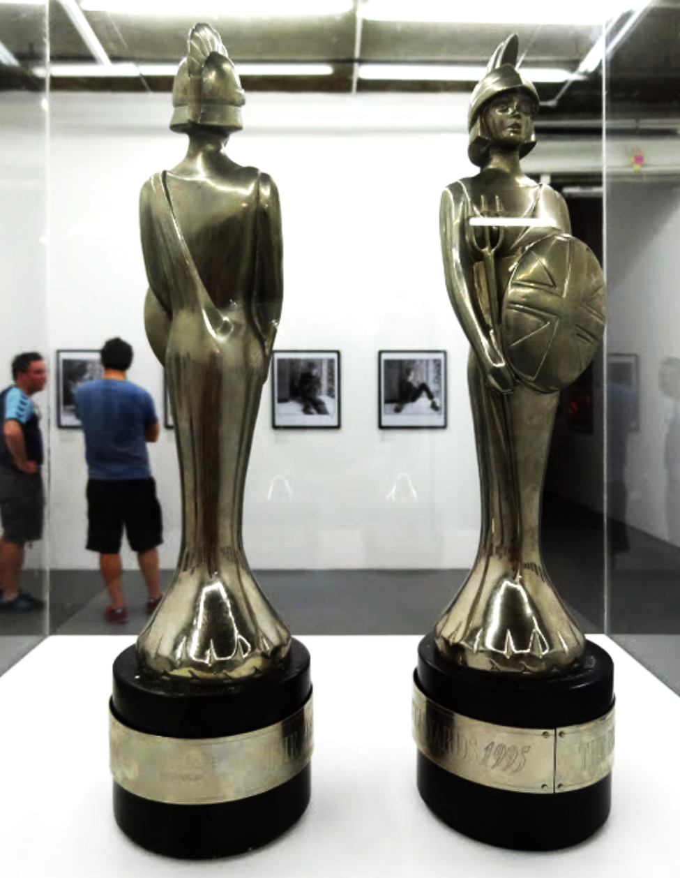 Pictured is two Brit Awards that the band previously won in a glass case, in front of the exhibition wall.