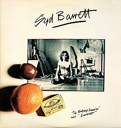 A shot of Syd Barrett  with a greenish filter over the top in the center of a beige vinyl cover with an orange, apple and small box in the left most corner of his photo. the top and bottom hand written note saying " Syd Barrett" and 