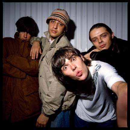 A shot of The Stone Roses (Left to right: Paul Slattery, Kevin Cummins & Ian Tilton) by a corregated wall